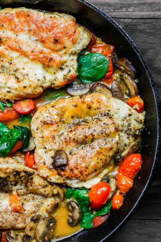 Italian skillet chicken with grape tomatoes and mushrooms in a white wine pan sauce in a cast iron pan