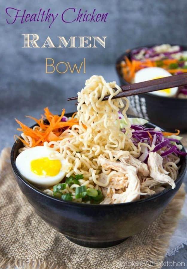 Healthy chicken ramen bowl with noodles lifted by chopsticks, a halved soft egg, shredded carrot and red cabbage