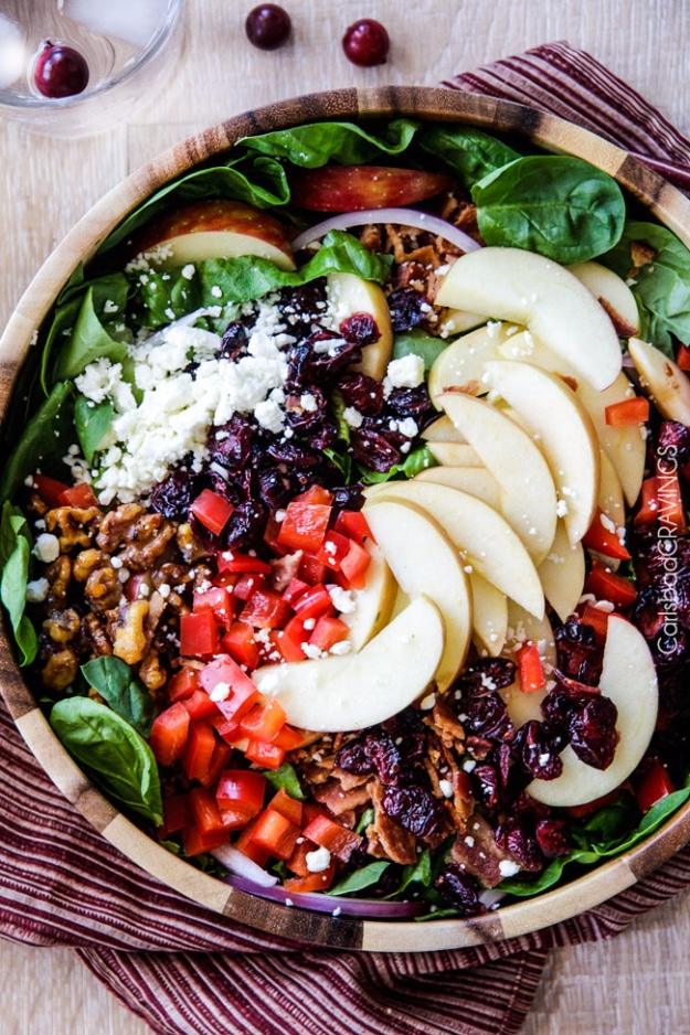 Apple cranberry salad with bacon, candied walnuts, feta and sliced apples in a large bowl with vinaigrette