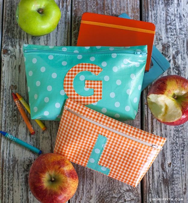 Two oilcloth zipper bags monogrammed G and L in aqua polka dot and orange gingham, with apples and crayons