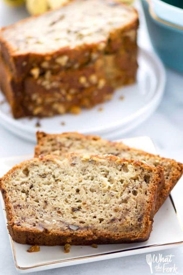 Gluten free banana bread loaf behind two thick slices on a gold rimmed plate showing walnut pieces in the crumb