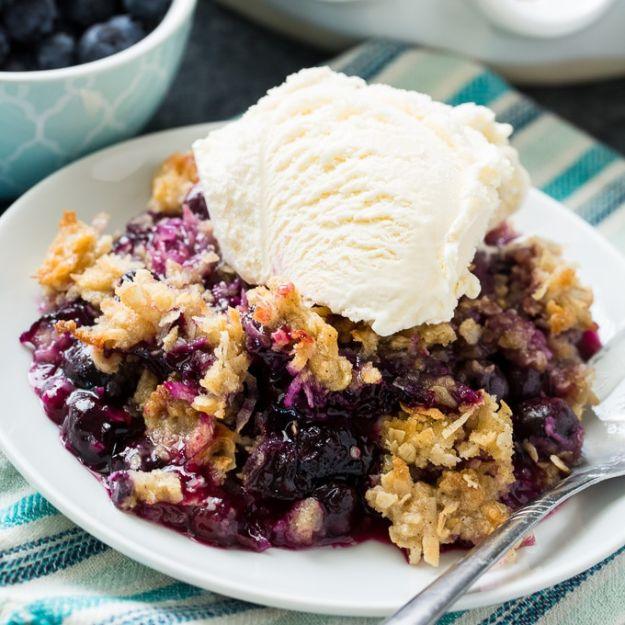 A serving of blueberry coconut crisp with a scoop of vanilla ice cream melting over the oat and coconut topping