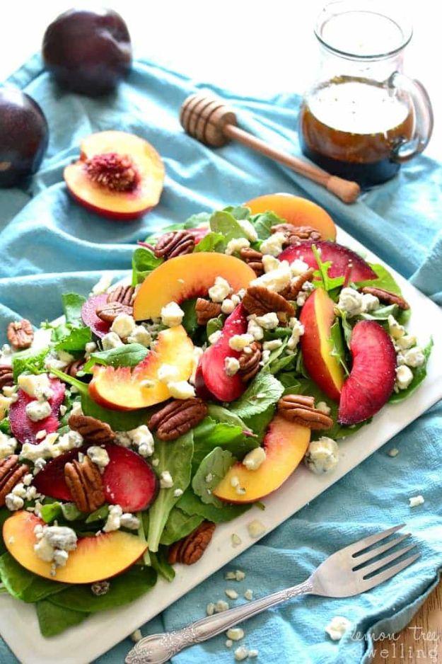 Stone fruit salad on a white platter with mixed greens, sliced nectarine and plum, pecans and blue cheese