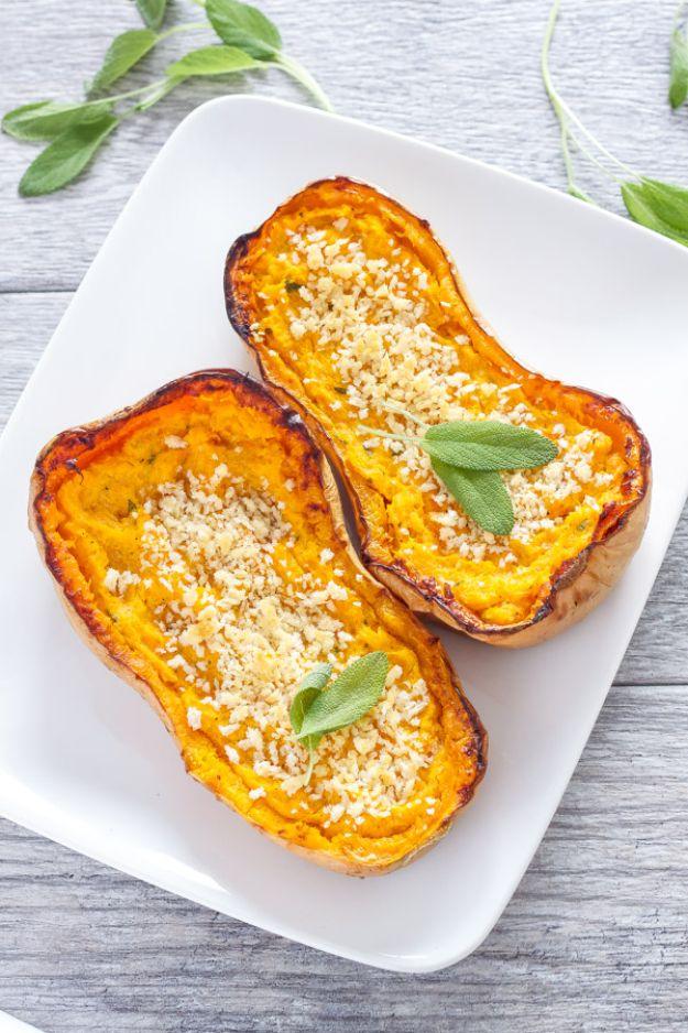 Twice baked butternut squash halves on a white plate topped with panko breadcrumbs and fresh sage leaves