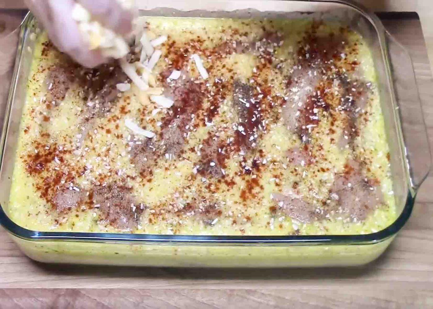 Adding shredded cheddar cheese on top of the chicken and rice casserole