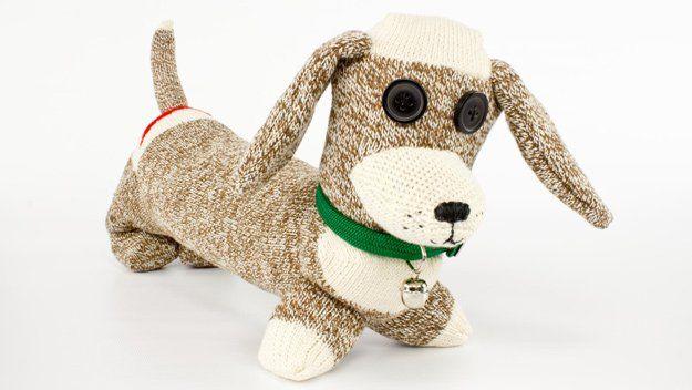 Stuffed dachshund shaped dog sewn from brown and cream marled socks, with black button eyes and a green collar with a bell