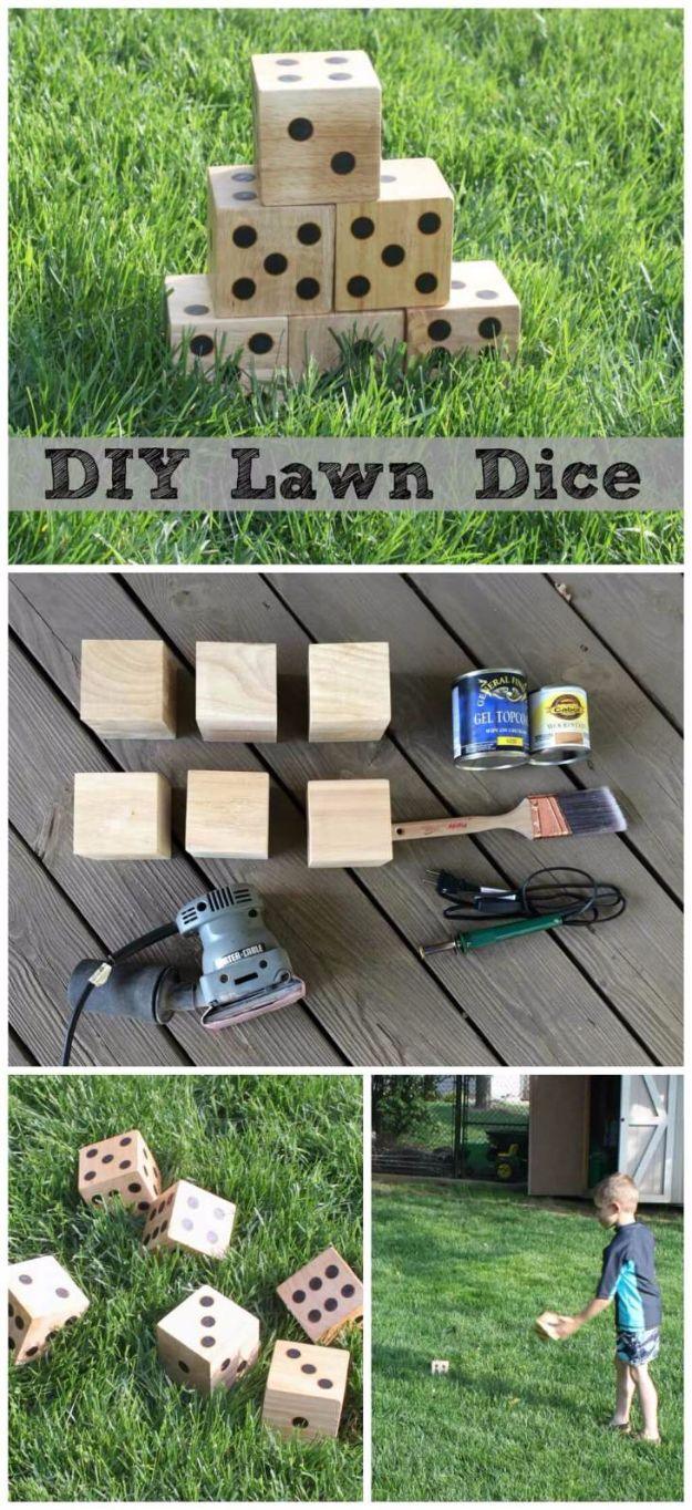 DIY wooden yard dice with burned dots stacked in a pyramid on the grass beside a sander and polyurethane can