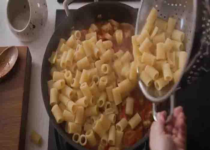 Tossing the pasta together with the tuscan chicken sauce