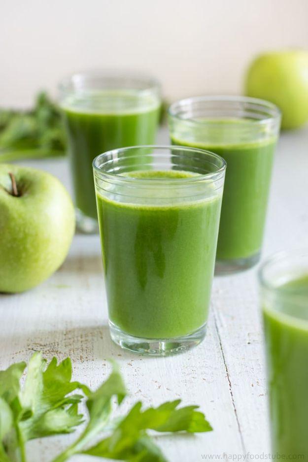 Glowing skin green juice poured into three glasses with a green apple and celery leaves on a pale counter