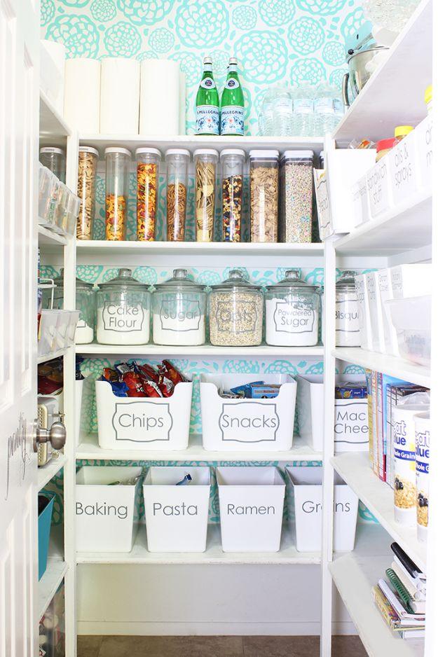 Pantry with turquoise floral wallpaper, clear canisters, labeled glass jars and white bins marked chips and snacks
