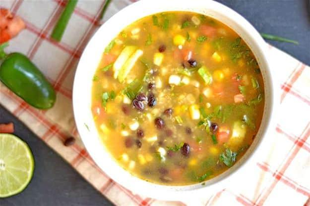Mexican black bean quinoa soup topped with diced avocado, chopped tomato, cilantro and sliced green onion
