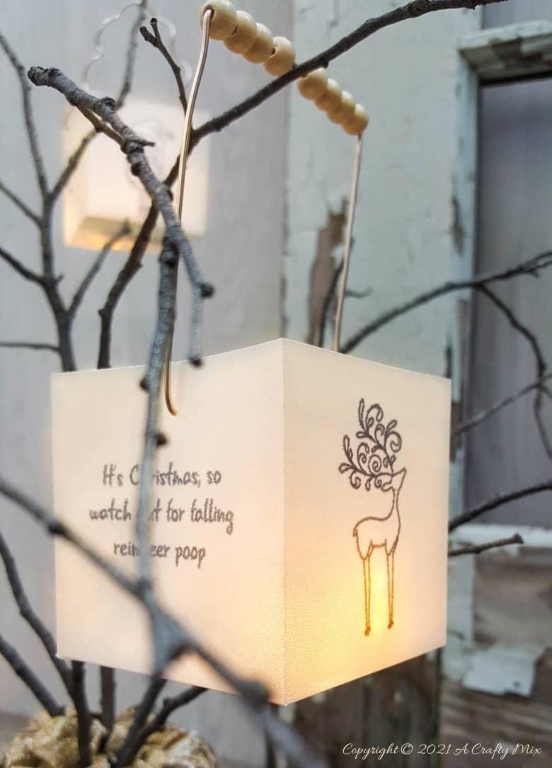 Row of small folded paper cubes lit from inside by string light bulbs sitting along a white mantel shelf