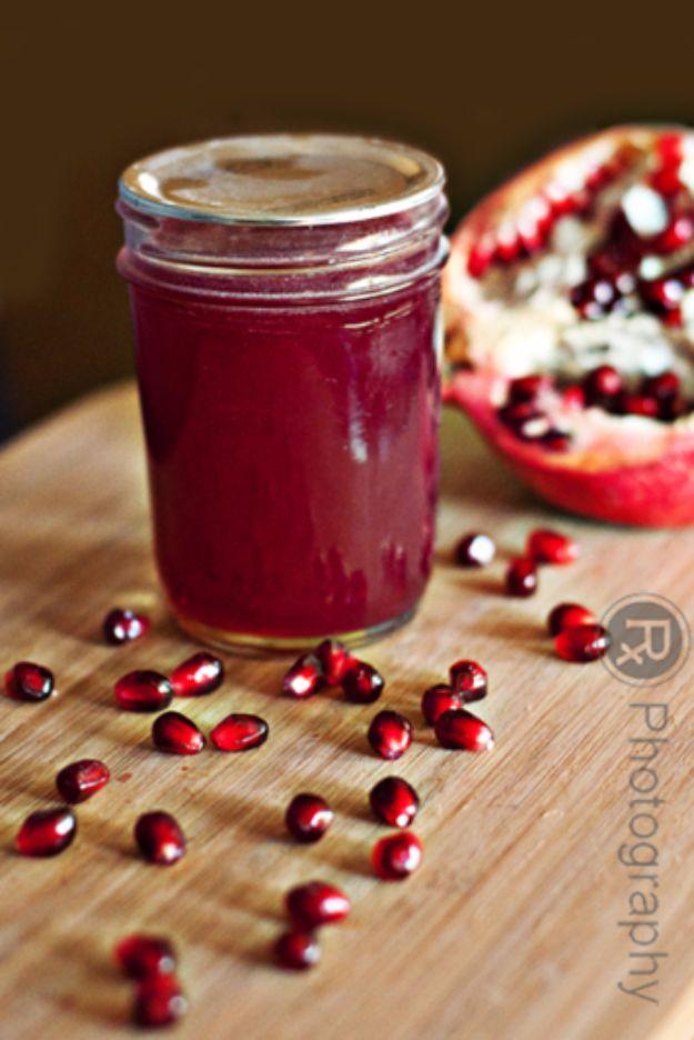 Pomegranate jelly in a small canning jar, clear deep red and fully set, beside fresh pomegranate seeds
