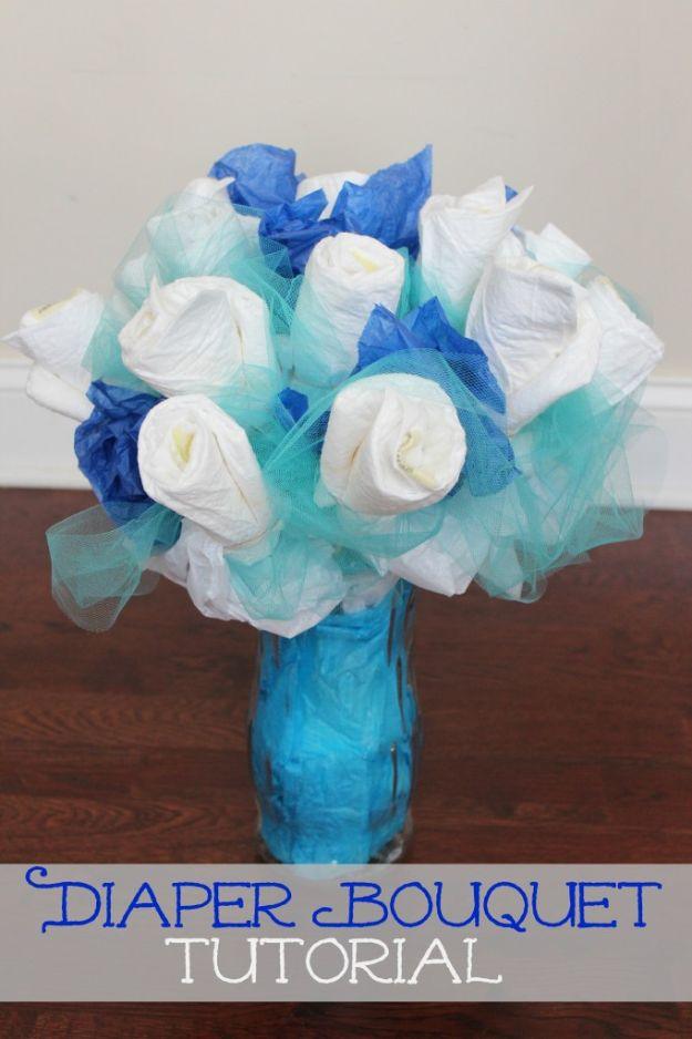 DIY baby shower decoration diaper bouquet with white rolled diapers and blue tulle in a blue glass vase