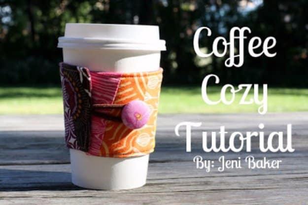 Patchwork fabric coffee cozy in orange, pink and brown prints buttoned around a white takeout cup on a weathered wood table