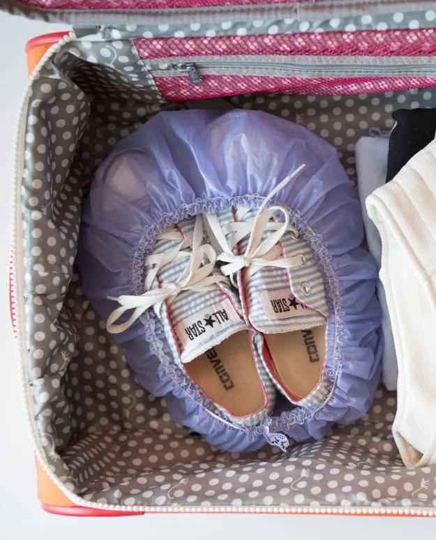 Purple hotel shower cap stretched over a pair of white canvas sneakers packed inside a polka dot lined bag