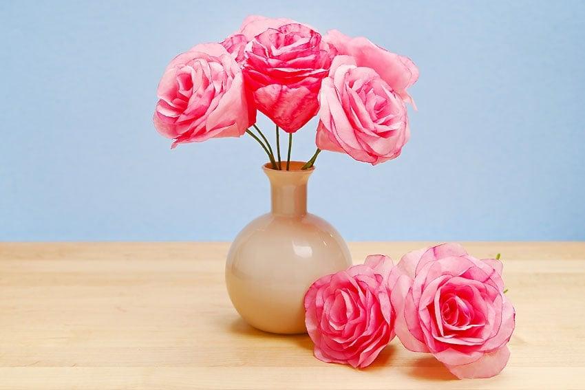 A soft bouquet of blush and cream coffee filter roses on wrapped floral wire, gathered with ribbon in a clear glass jar