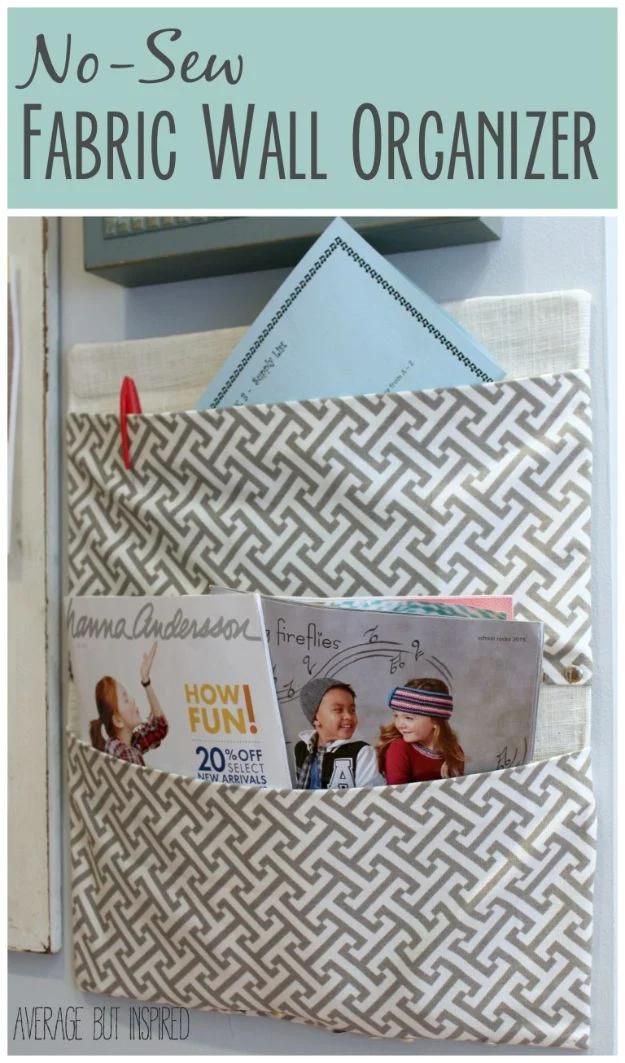 Gray and white geometric fabric covered wall pocket holding two catalogs and a blue envelope, hung on a pale wall