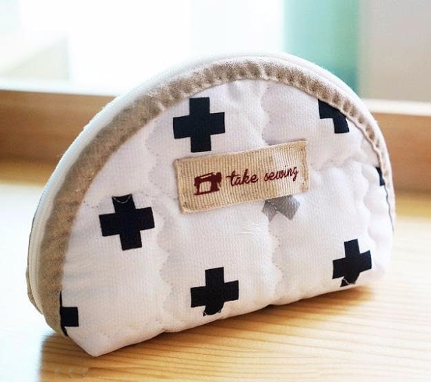 Half moon zip pouch in white quilted cotton with black crosses bound in oatmeal linen with a woven label