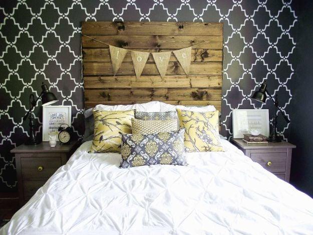 Envelope pillows in Aviary yellow sparrow and gray damask prints on a white bed under a pallet wood headboard