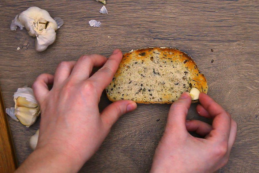 Rubbing a cut clove of garlic over a slice of toasted bread