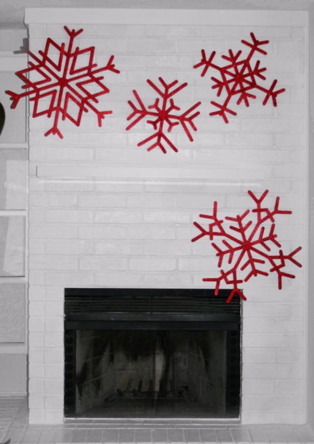 Four large red popsicle stick snowflakes arranged in a scatter across a white painted brick fireplace
