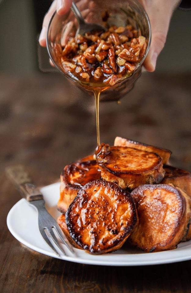 Melting sweet potato rounds roasted golden and crisp under a maple pecan sauce on a white serving plate