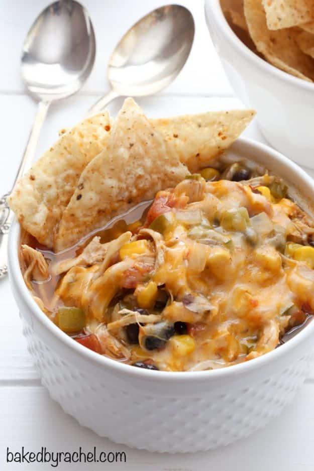 Slow cooker black bean taco chili topped with melted cheese and tortilla chips with two spoons beside
