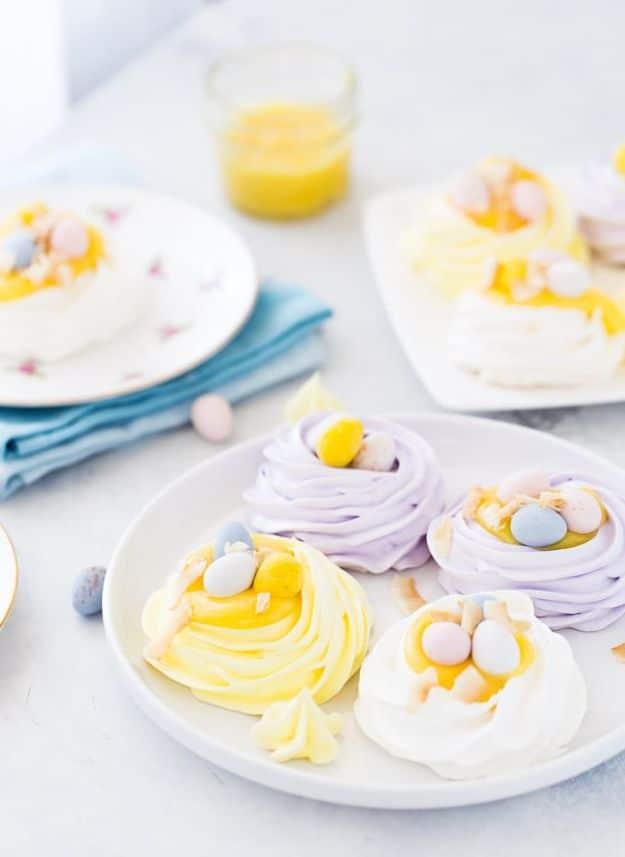 Pastel yellow and lilac coconut meringue nests filled with cream and topped with small speckled candy eggs