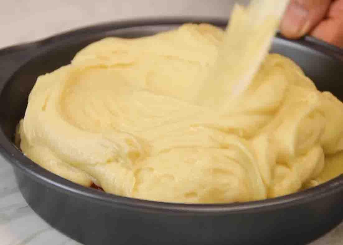 Adding the pineapple upside down cake batter to the cake pan