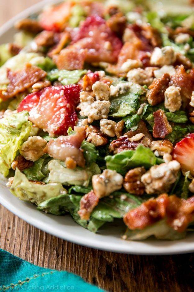 Strawberry bacon salad on a white platter with romaine, sliced strawberries, bacon, pecans and blue cheese