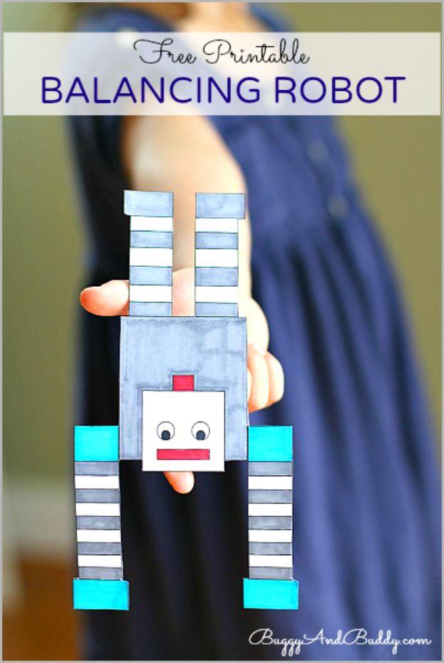 Balancing robot, a colored paper robot with a square head and striped arms balanced on a fingertip against a navy dress