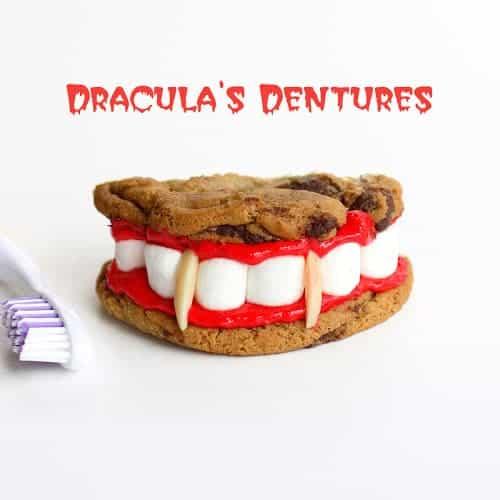Chocolate chip cookie sandwiches with red frosting, mini marshmallow teeth and almond vampire fangs for Halloween