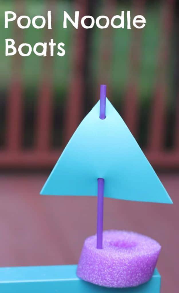 Purple pool noodle slice boat with a blue foam triangle sail threaded on a purple straw, on a blue table outdoors