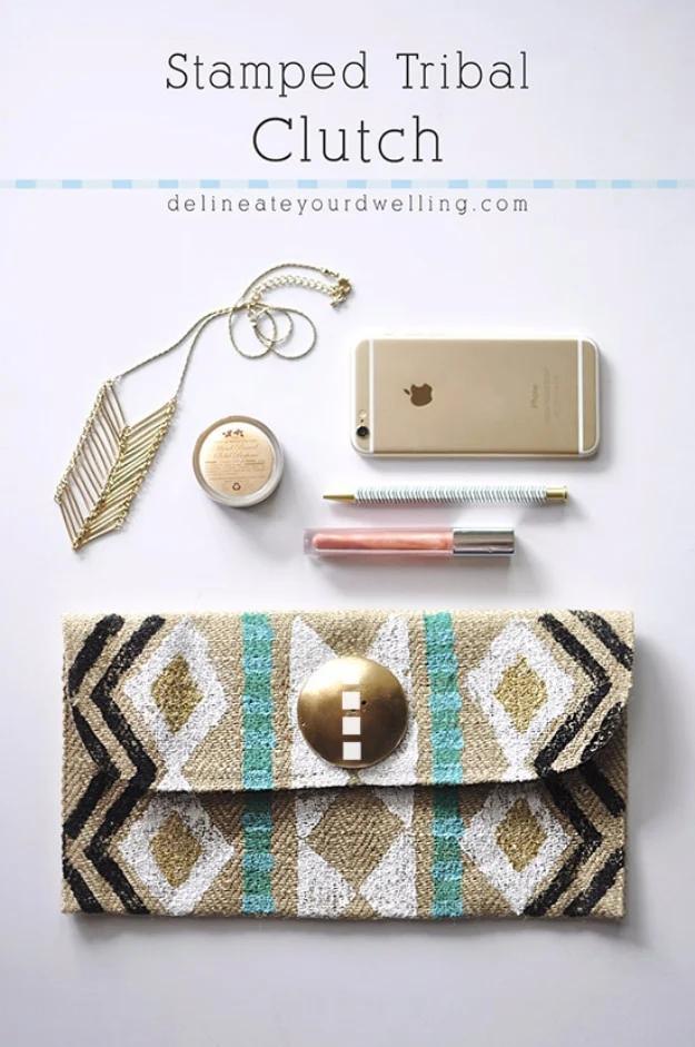 A natural canvas clutch hand stamped with black triangles and stripes, lying flat on a white cotton bedspread