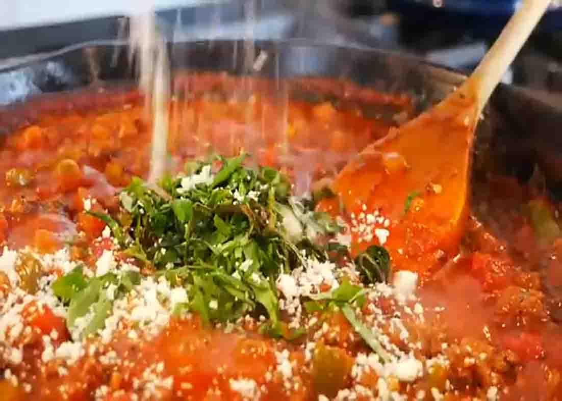 Garnishing the ground beef skillet with chopped basil and shredded parmesan