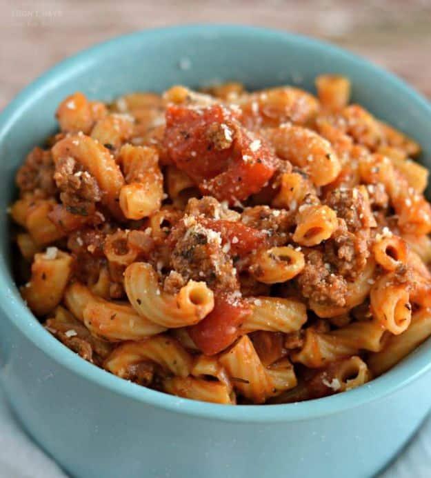 Turquoise bowl of instant pot goulash with elbow macaroni, ground beef, tomato sauce and grated parmesan on top