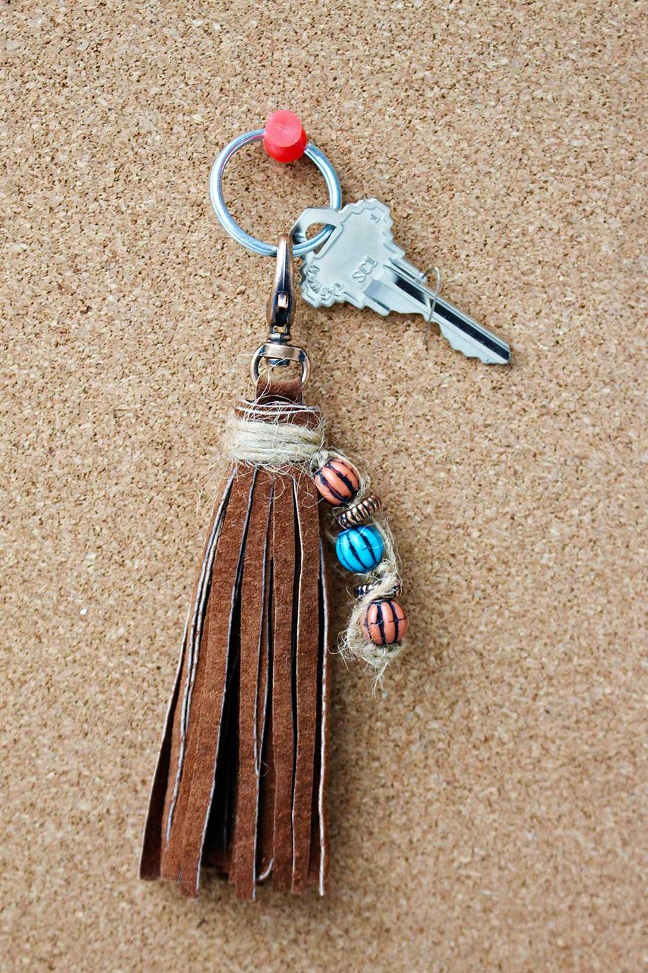 Brown leather fringe tassel keychain strung with small beads on twine, hanging from a key ring with two keys