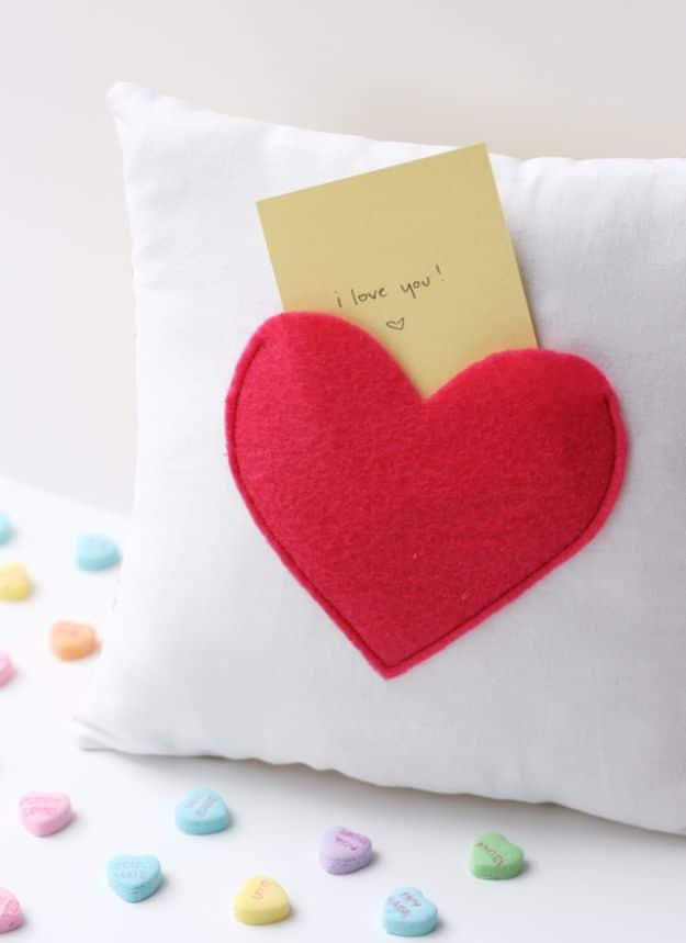 A small fabric pillow with a felt heart pocket holding a folded love note, a handmade Valentine gift for her