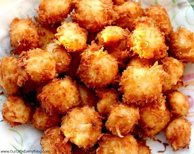 Pile of golden gluten free coconut shrimp on a white plate with a blog watermark across the bottom corner