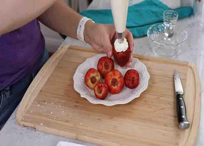 Adding the cheesecake filling to the strawberries