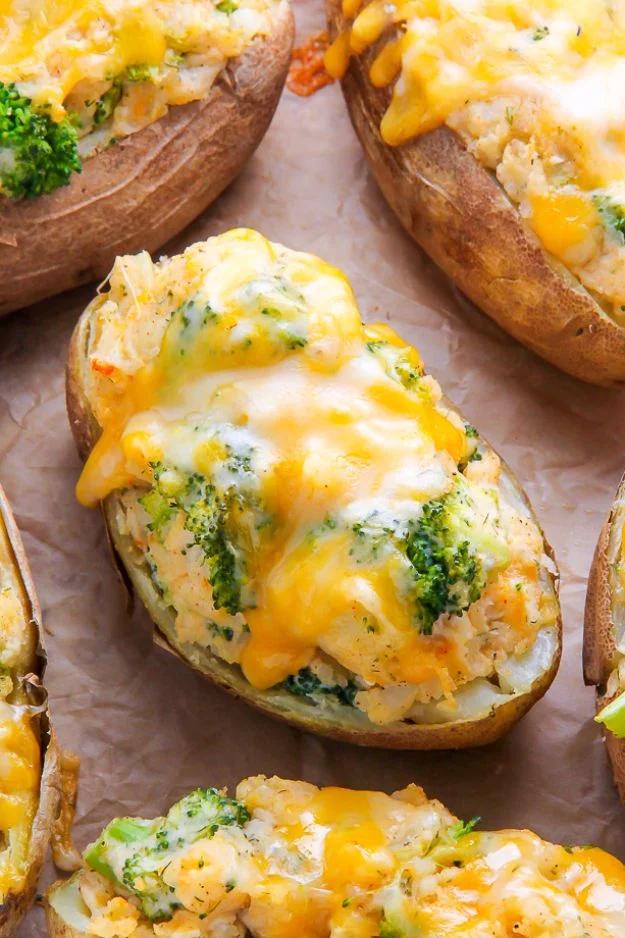 Broccoli and cheddar twice baked potato halves with melted orange cheese and broccoli florets on parchment