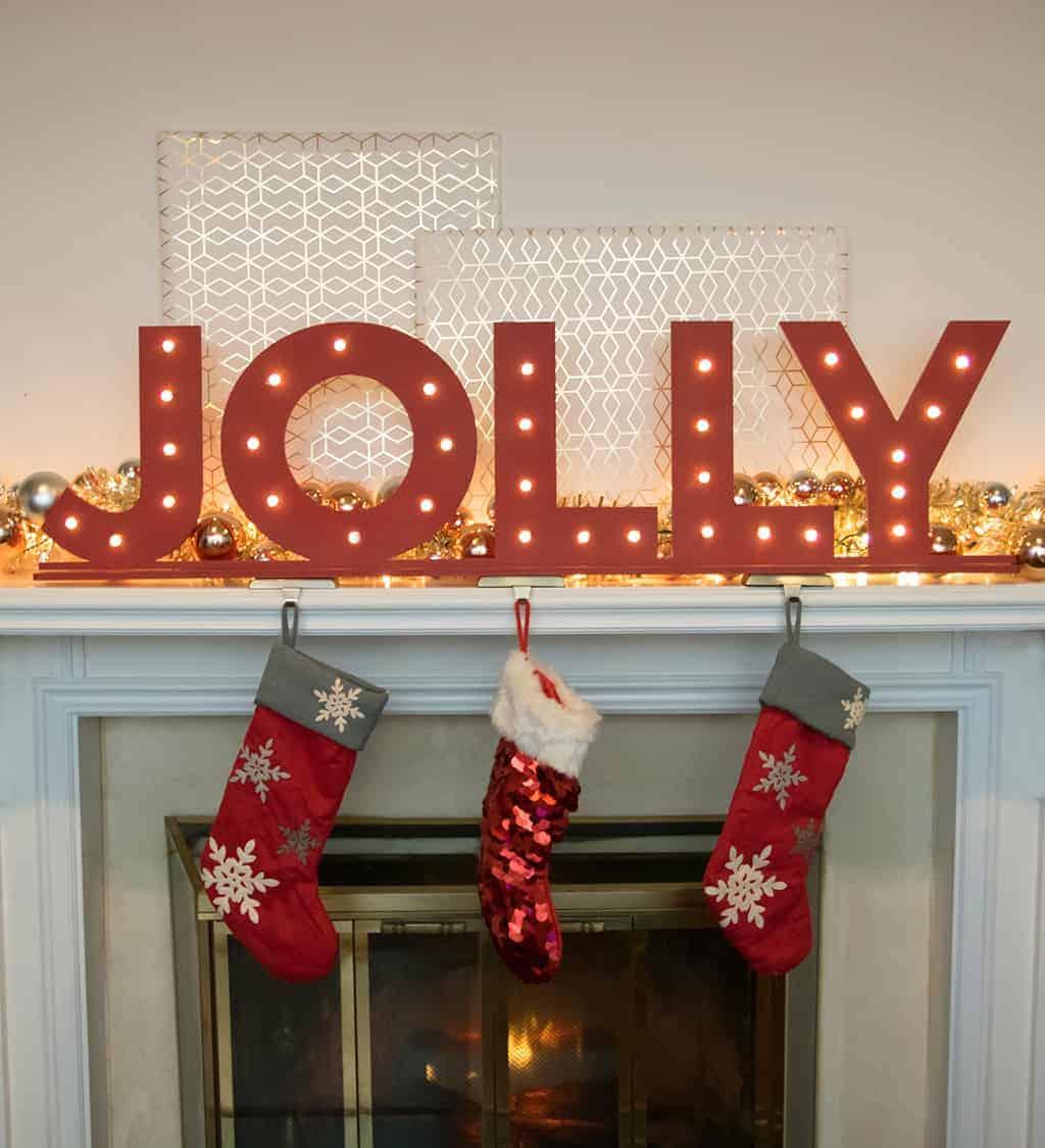 Freestanding wooden letters spelling a holiday word with round bulbs set into the faces glowing on a console