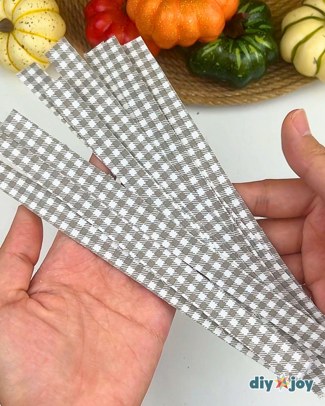 Easy Crafts - a hand holding several cut gray gingham fabric tape strips fanned out against a white background