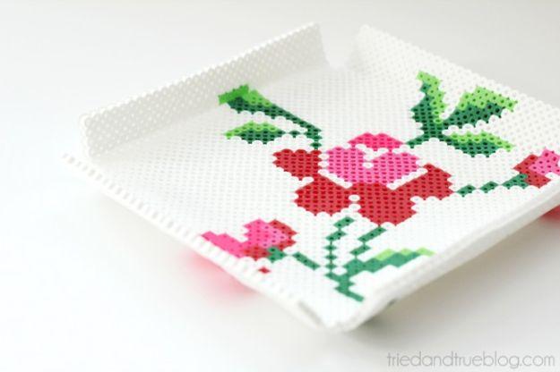 Perler bead tray, a white beaded square tray with folded sides and a pink and red rose cross stitch design