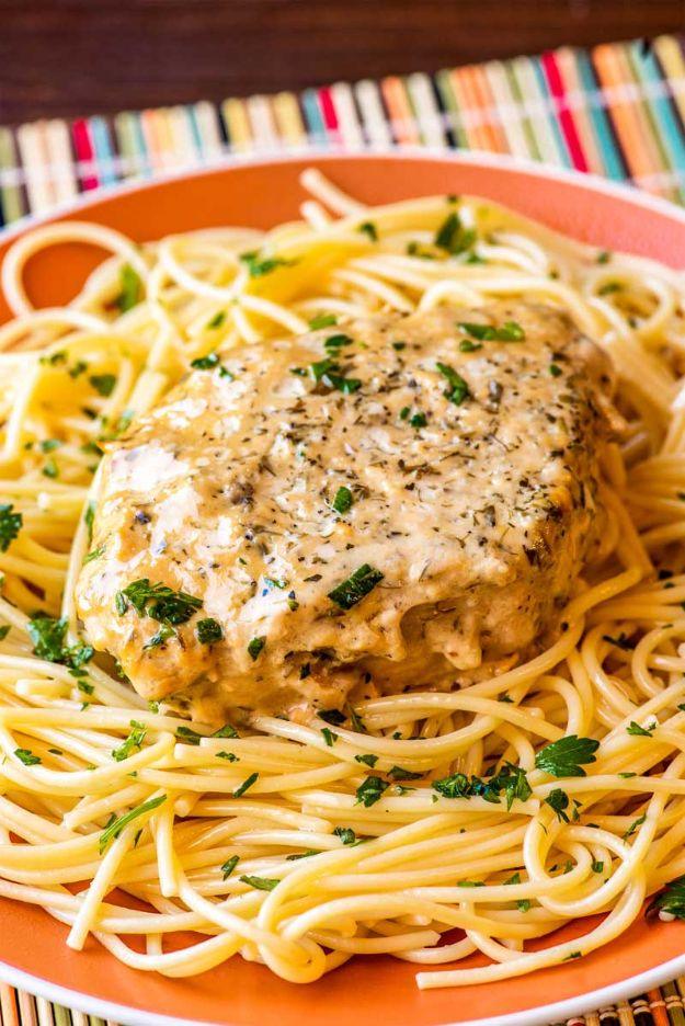 Crock pot ranch pork chop served over linguine in a thick creamy herb sauce with chopped parsley on top