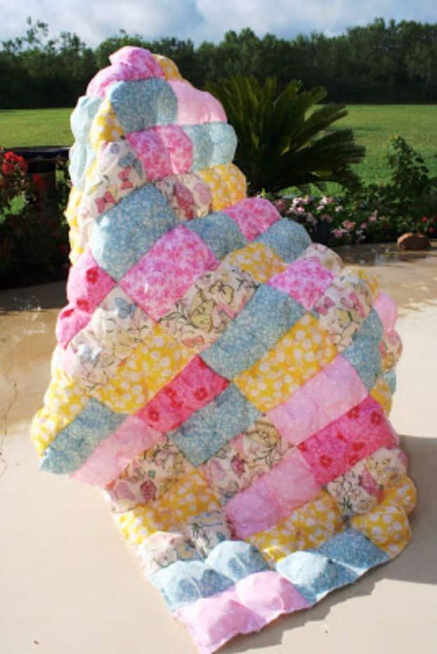 Easy puff quilt in pink, yellow and blue florals, thick stuffed squares standing upright on a patio in a garden