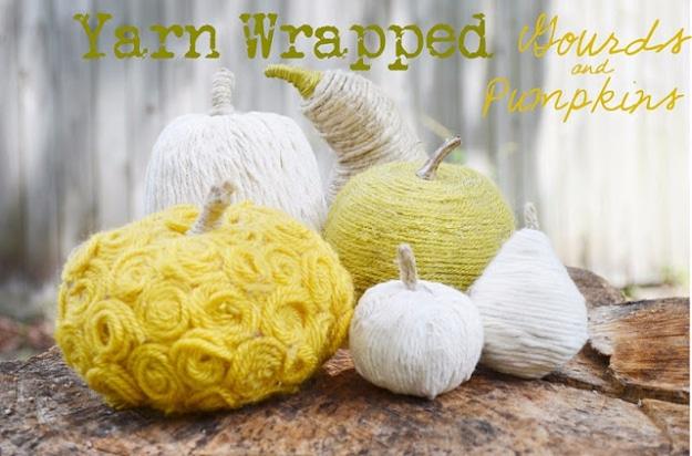 Yellow, ivory and green yarn wrapped faux pumpkins and gourds grouped on a cut tree stump out of doors