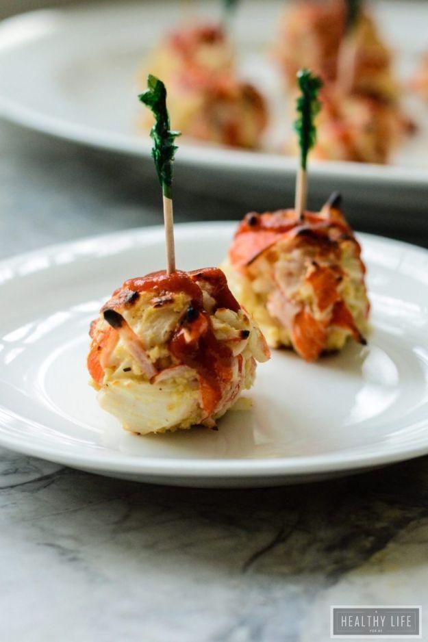 Spicy crab bites broiled golden on a baking sheet and topped with sriracha, a gluten free party appetizer