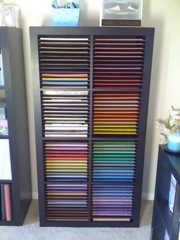 Dark IKEA cube bookcase fitted with thin internal shelves, each cube filed with 12x12 scrapbook paper sorted by color